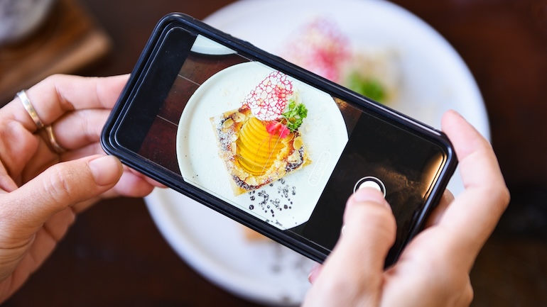 Someone taking a photo with their phone of a plate of food.