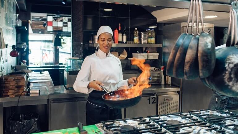 Female chef using restaurant equipment in a commercial kitchen.