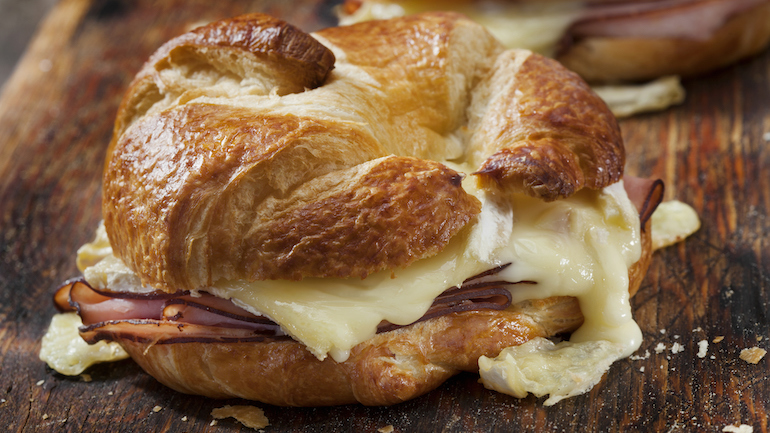 Close up of a baked ham and brie croissant sandwich.