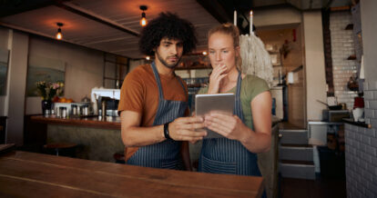 Two restaurant workers looking at a mobile tablet.