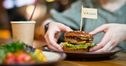 A person holding a vegan hamburger.