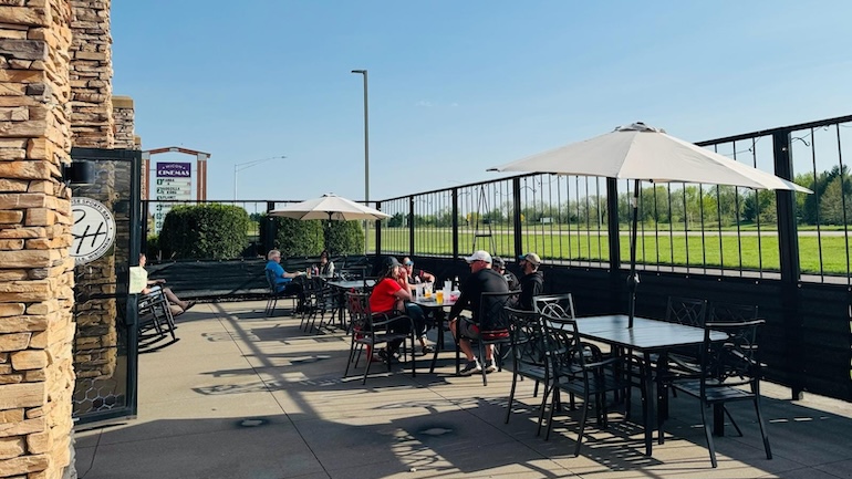 Rally House Sports Bar outdoor patio, which has black tables with white umbrellas.