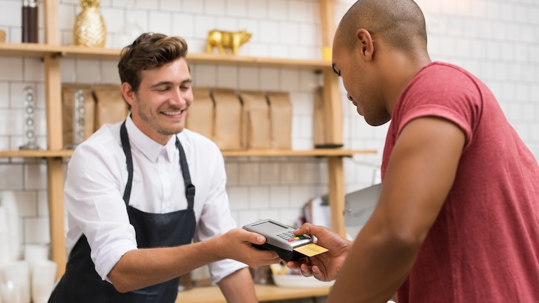 Restaurant staff holding credit card swipe machine while customer is paying using his credit card.