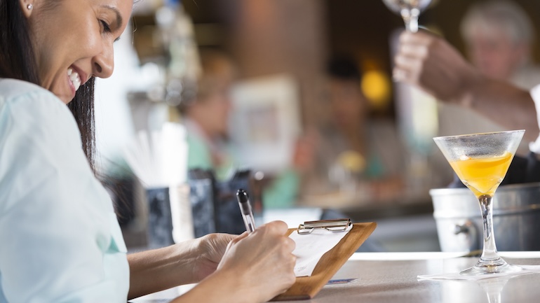 Woman signing a receipt after paying the bill at a restaurant.