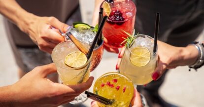 A close up photo of a group of people cheering their drinks.