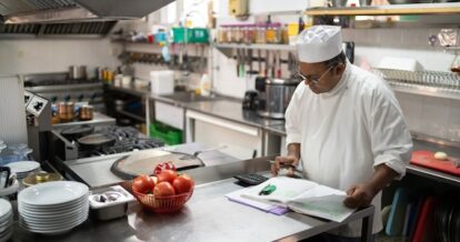 A chef doing paperwork in a kitchen.